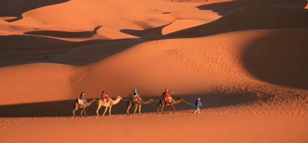 People riding camels across the Sahara Desert, which is one of the best places to visit in Morocco