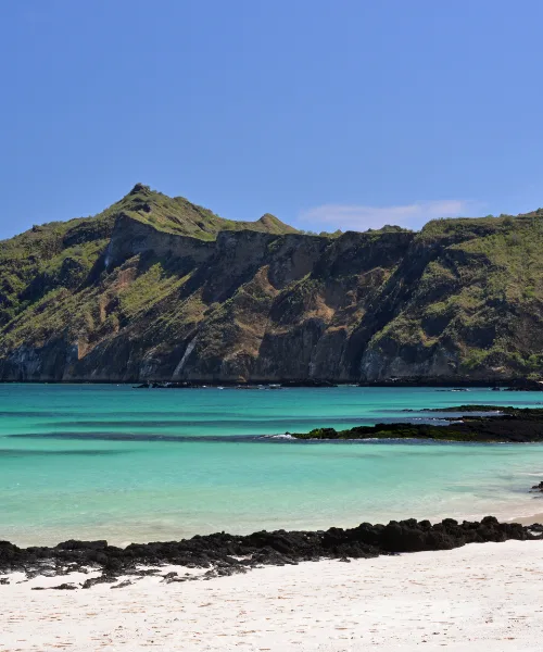 White sand beach with steep mountains in the Galapagos