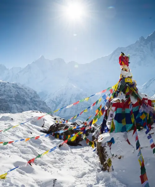 Prayer flags at the top of a snowy mountain in Nepal